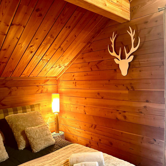 Décoration murale tête de cerf en métal, installée dans une chambre chalet en bois à Briançon – Serre Chevalier, création artisanale design.